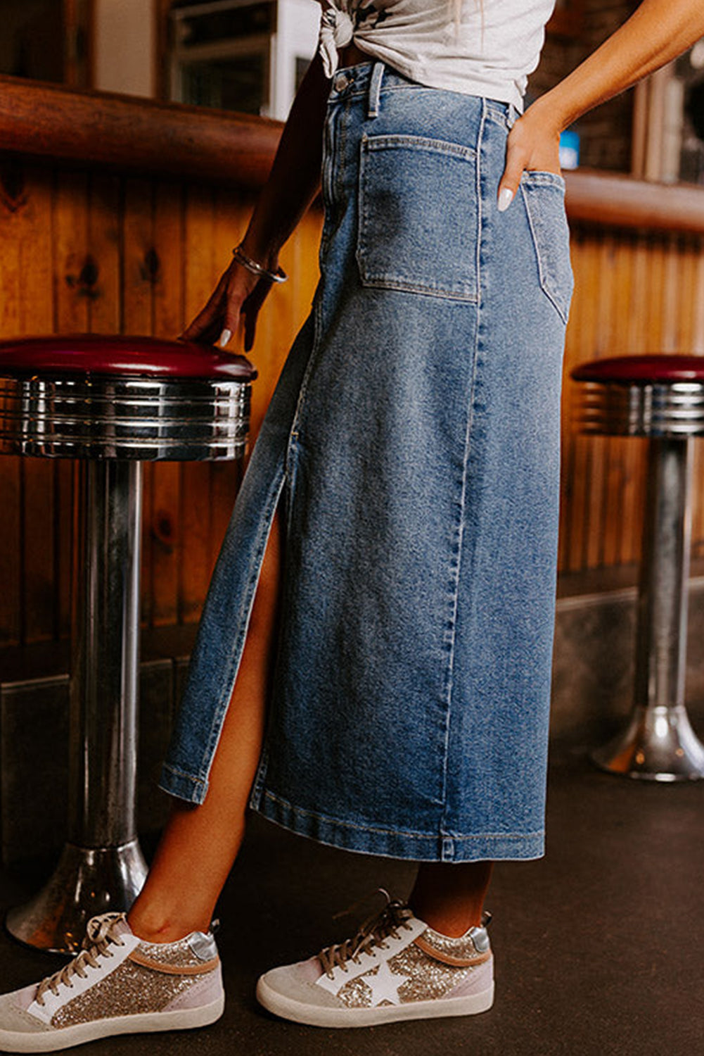 A chic front slit midi length denim skirt in blue, featuring a high-waist design and four practical patch pockets. 