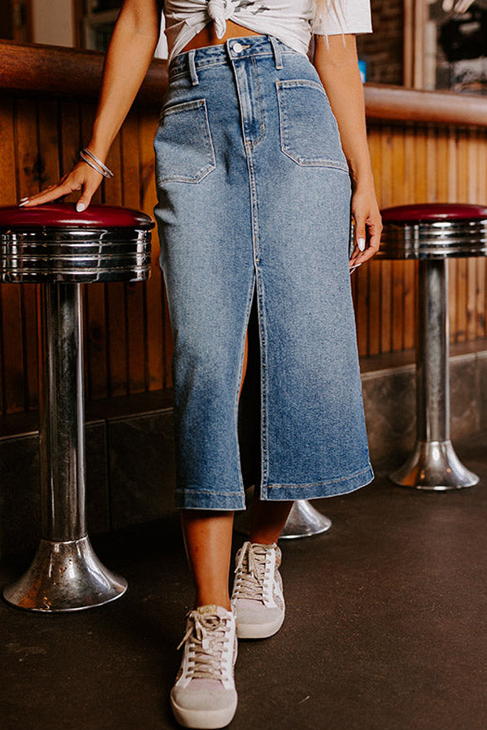 A chic front slit midi length denim skirt in blue, featuring a high-waist design and four practical patch pockets. 