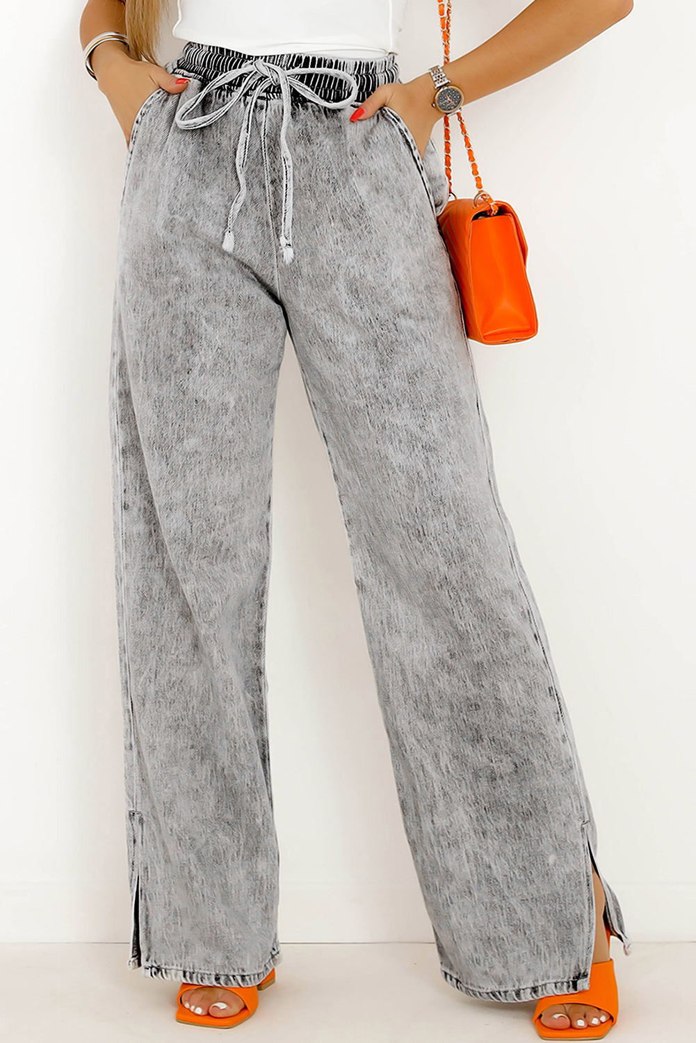 A stylish pair of grey drawstring waist denim pants from a cotton blend fabric, designed with a wide leg for a relaxed yet flattering fit. Perfect for laid-back days!