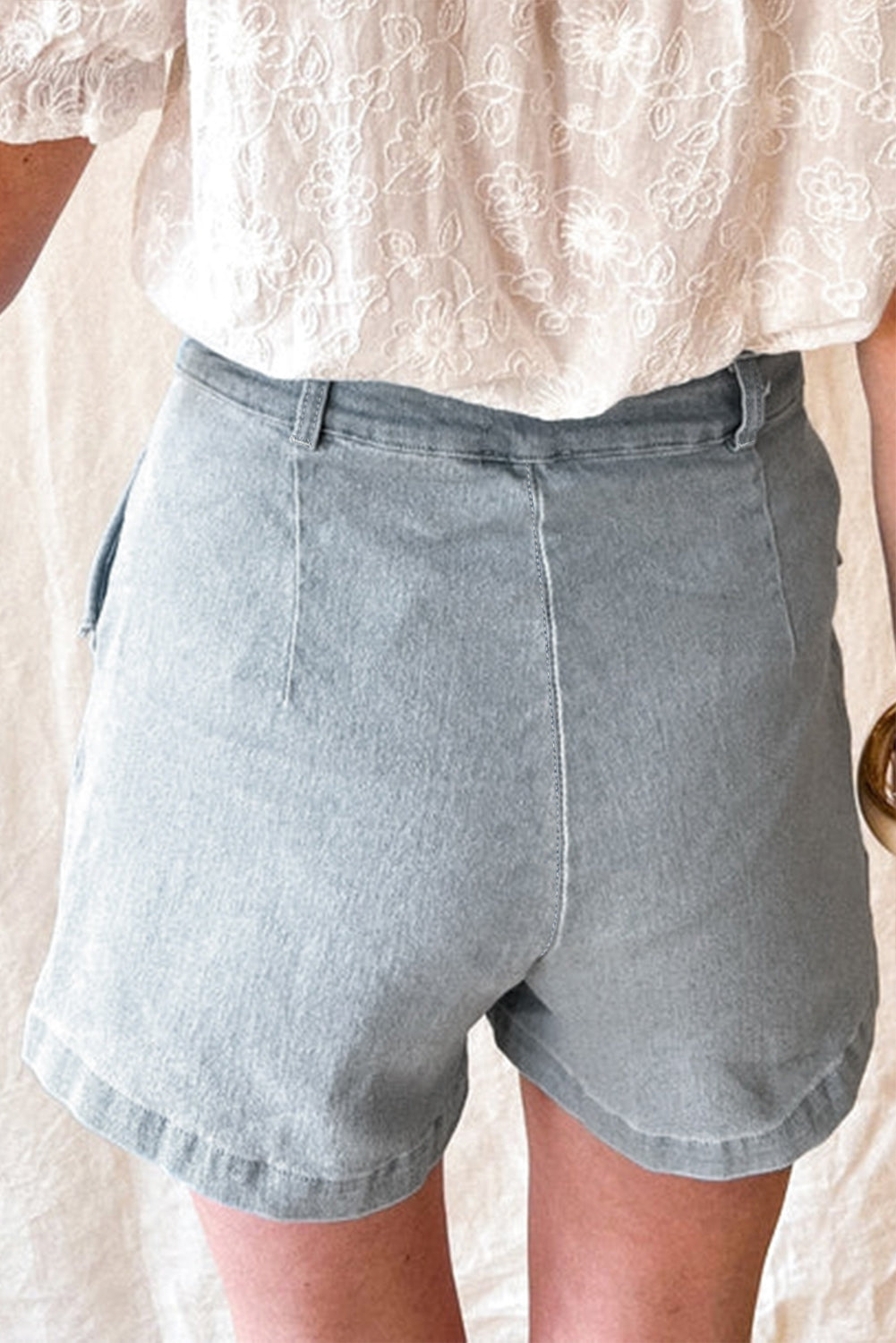 Trendy and practical women's jean shorts with a high waist, ruffled detailing, and convenient flap pockets.