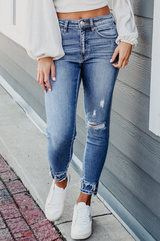 Light blue skinny jeans with unique distressed design and frayed ankles.