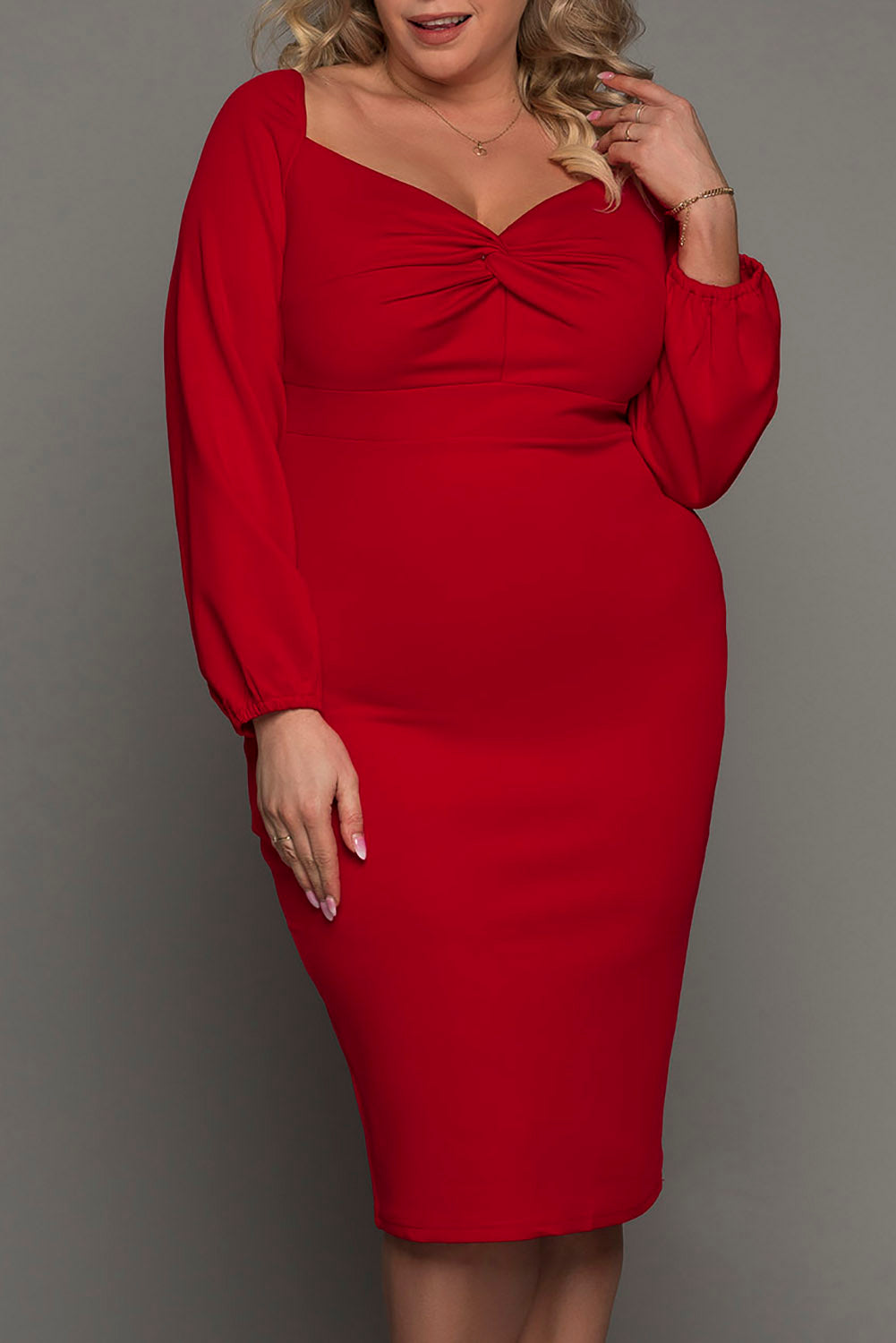 A woman wearing a blue long sleeve dress with a front knot detail at the waist, in a plus size midi length