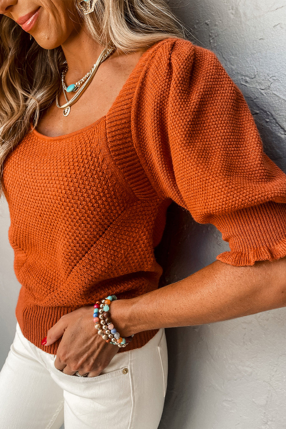 Woman wearing a fashionable Gold Flame Textured Knit Top with a stylish square neckline, trendy puff sleeves, and a chic ribbed hem – a unique blend of comfort and style.