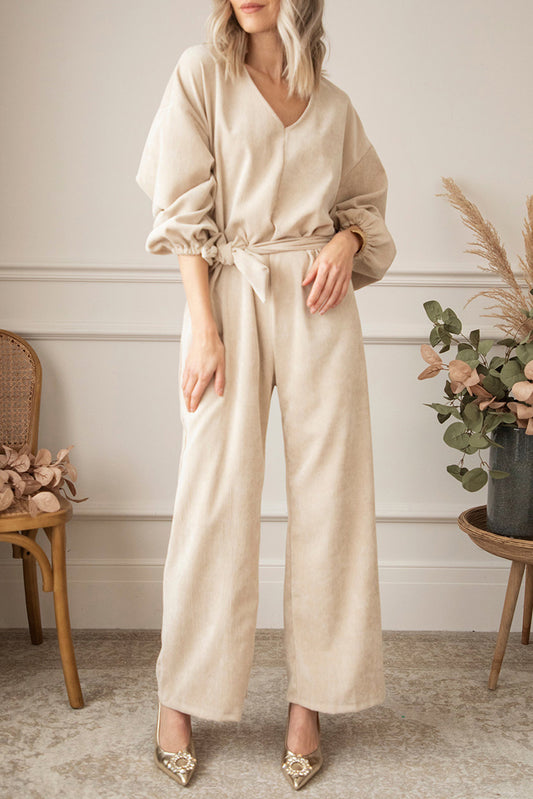   Keyhole Back V Neck Tie Waist Loose Jumpsuit featuring a v-neckline, puff sleeves, a sash tie at the waist, and wide-leg bottoms.