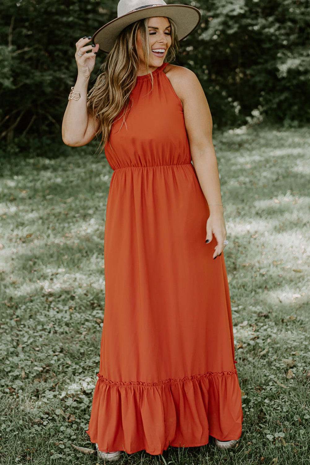 Plus size fashionista stunningly showcasing a sleeveless long dress featuring an elegant ruffled hem, perfect for summertime outings and special celebrations.