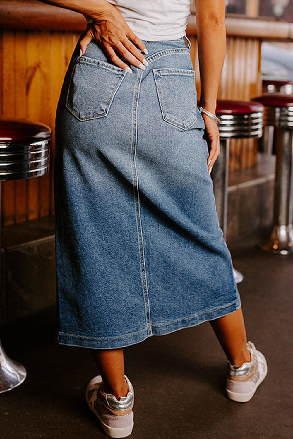 A chic front slit midi length denim skirt in blue, featuring a high-waist design and four practical patch pockets. 