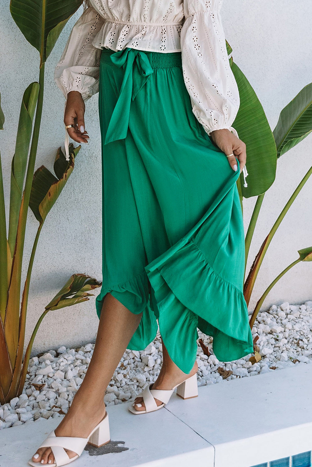 A stunning green high-waisted maxi skirt featuring an asymmetrical flounce, belted waist, and a chic look to complete any outfit.