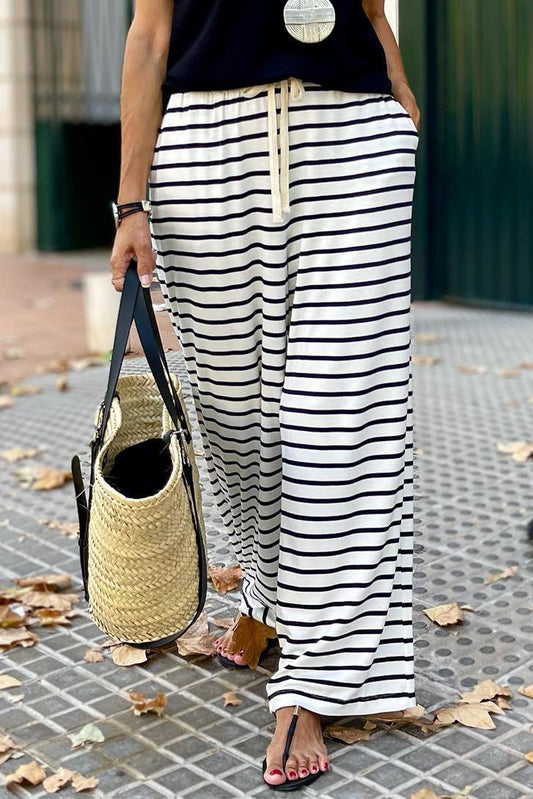 A pair of white wide leg pants with thin black stripes and drawstring closure.