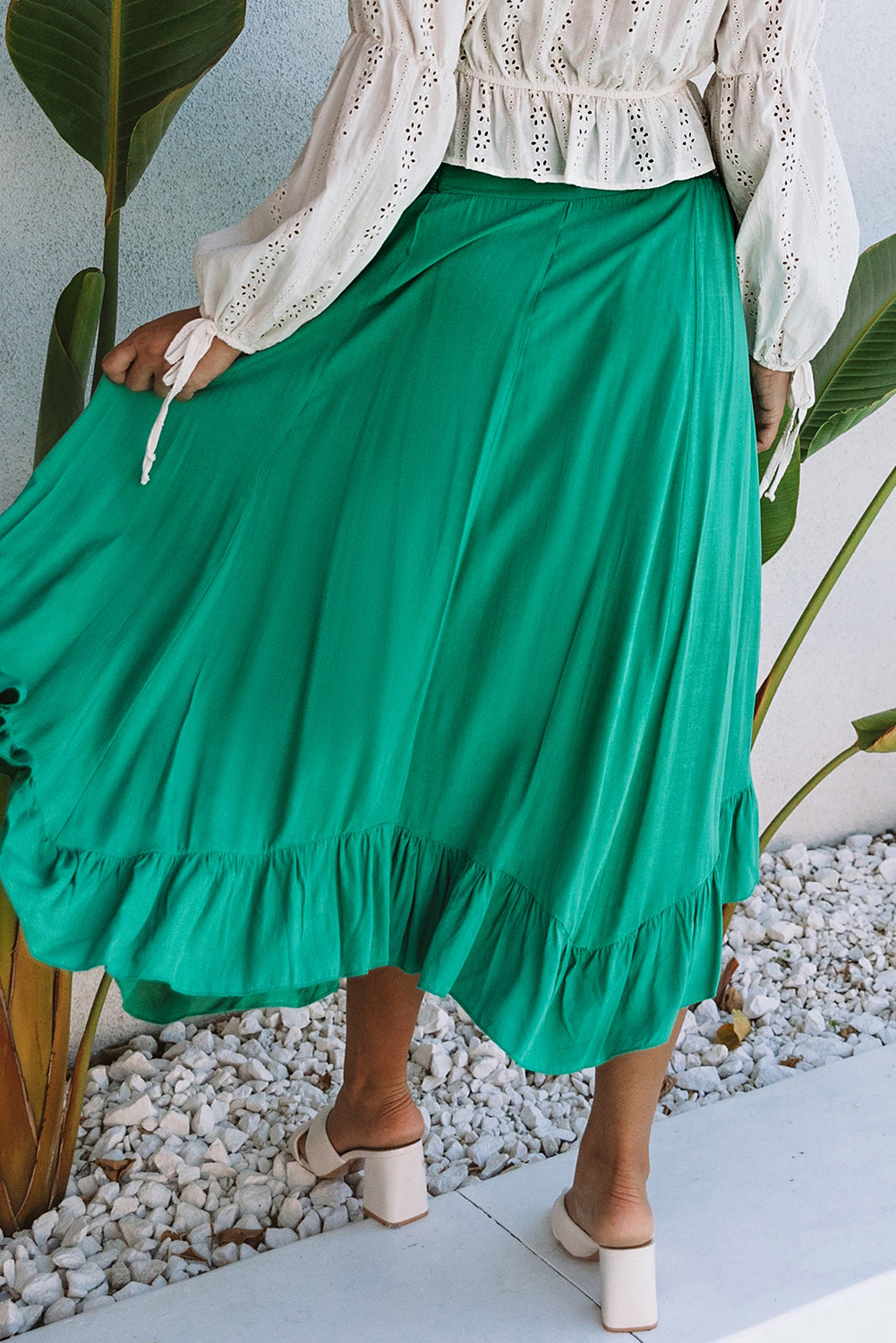 A stunning green high-waisted maxi skirt featuring an asymmetrical flounce, belted waist, and a chic look to complete any outfit.