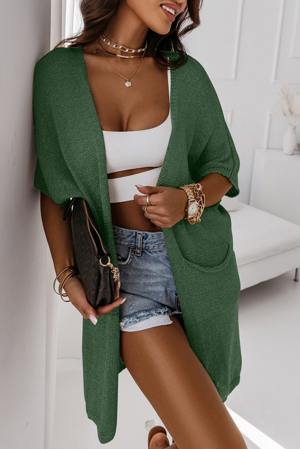 A green dolman half sleeve cardigan with two pockets in a relaxed, long fit.