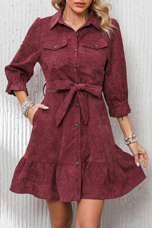 Red Dahlia corduroy dress with collared neck, button front, attached belt, and ruffled hem.